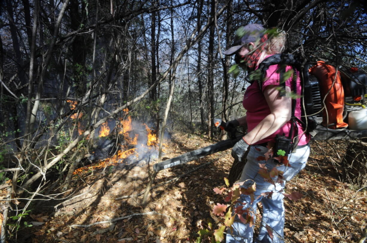 Volunteer firefighter Sheri Torbett, with the Sequoyah Volunteer Fire Department, uses a leaf blower to turn back approaching flames near the Mowbray Volunteer Fire Hall in Soddy-Daisy, Tenn. Federal authorities say warmer-than-average temperatures and no rainfall are deepening a drought that&#039;s sparking forest fires across the Southeastern U.S. But in North Carolina, at least 20 wildfires are being investigated as suspected arson, officials said.