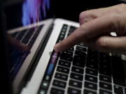 A guest looks at the Touch Bar on a MacBook computer shown in a demo room following the announcement of new products Oct. 27 at Apple headquarters, in Cupertino, Calif. Higher-end models of Apple&#039;s MacBook Pro now come with a narrow touch screen above the regular keyboard for quick access to common settings and tasks.