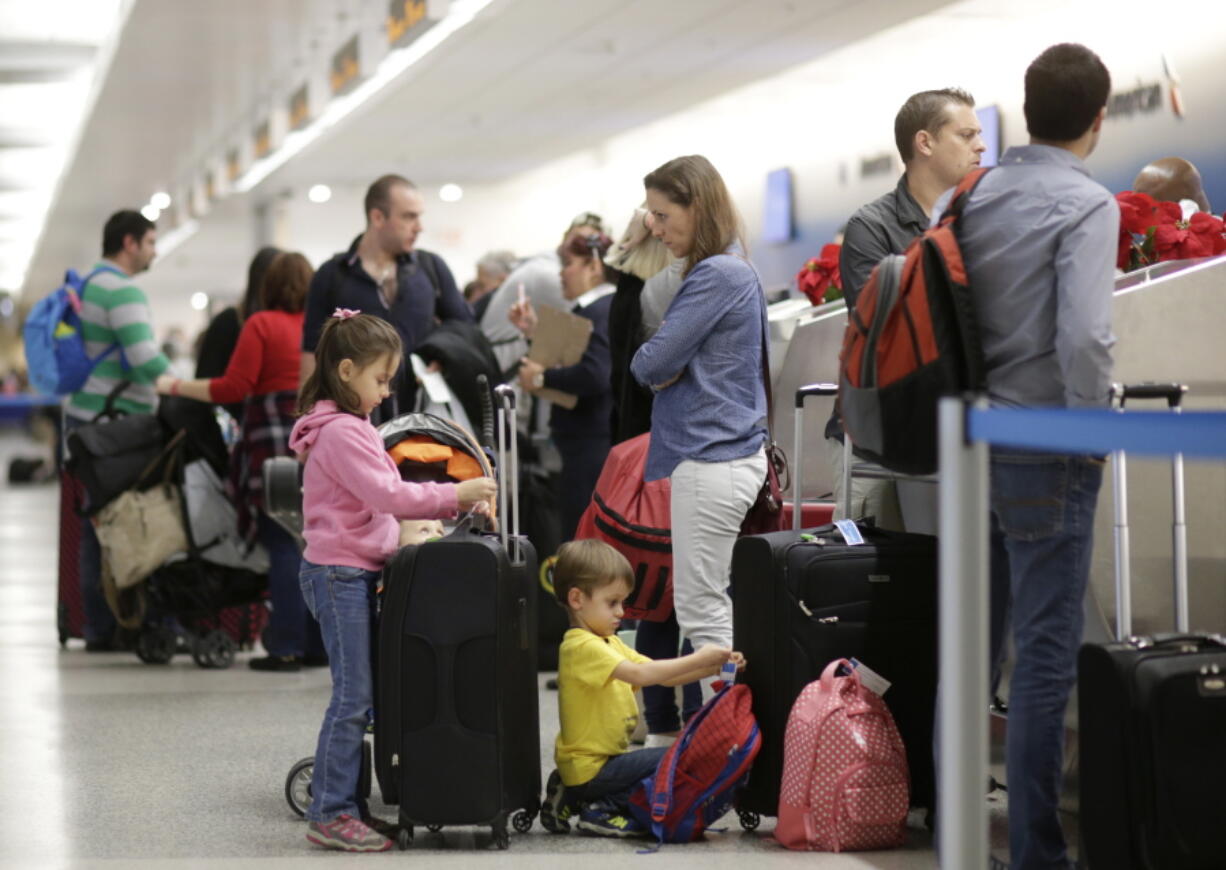 Carola Vazquez, center, waits at the ticket counter with her children Isabel, left, and Diego, kneeling, while traveling to Cancun, Mexico from Miami International Airport in Miami on Nov. 25, 2015. An airline trade group said Wednesday, Nov. 2, 2016 that about 27.3 million people will fly on U.S. airlines over a 12-day period that starts Nov. 18 and ends the Tuesday after Thanksgiving. That&#039;s up 2.5 percent from last year.