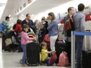 Carola Vazquez, center, waits at the ticket counter with her children Isabel, left, and Diego, kneeling, while traveling to Cancun, Mexico from Miami International Airport in Miami on Nov. 25, 2015. An airline trade group said Wednesday, Nov. 2, 2016 that about 27.3 million people will fly on U.S. airlines over a 12-day period that starts Nov. 18 and ends the Tuesday after Thanksgiving. That&#039;s up 2.5 percent from last year.