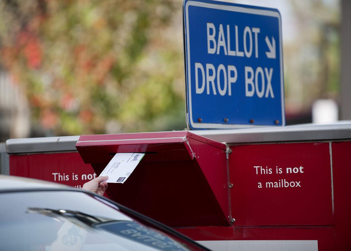 A voter drops off a ballot in the drop box on West 14th Street.