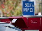 A voter drops off a ballot in the drop box on West 14th Street.