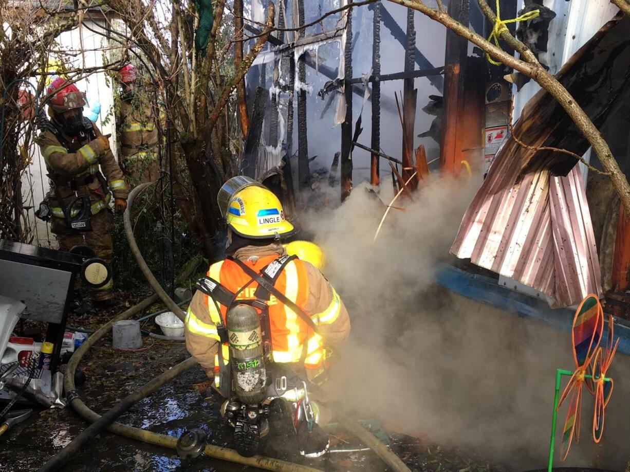 George Lingle, center, and other firefighters respond to a fire at a mobile home park in Woodland late morning Tuesday. The fire destroyed the home and displaced an occupant.