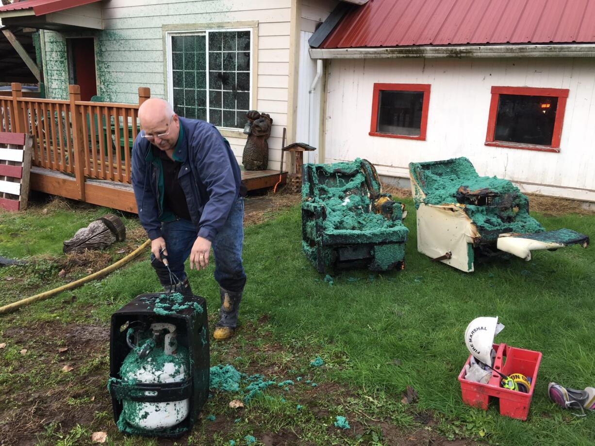 Clark County Deputy Fire Marshal Curtis Eavenson inspects some of the wreckage Tuesday afternoon after a barn fire south of Ridgefield. The blue-green slurry came from a hydroseed truck, which a bystander used to help douse the fire before firefighters arrived.