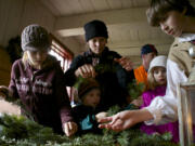 The Gilliland family of Woodland -- Noel, from left, William, Kathleen and Charlee -- get help from a re-enactor as they make wreaths during the 2013 Christmas at Fort Vancouver event.