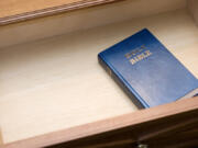 A Bible sits in a hotel room nightstand open drawer.