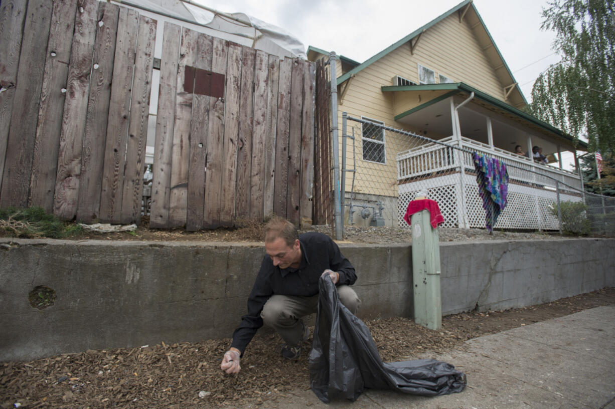 Share House resident Michael Utton clears cigarette butts from around the exterior of the building during a September cleanup by volunteers.