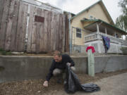 Share House resident Michael Utton clears cigarette butts from around the exterior of the building during a September cleanup by volunteers.