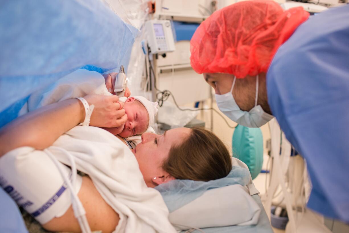 Amber Baker holds baby Cora immediately after her C-sectin earlier this month, while husband Kody Baker looks at his daughter for the first time.