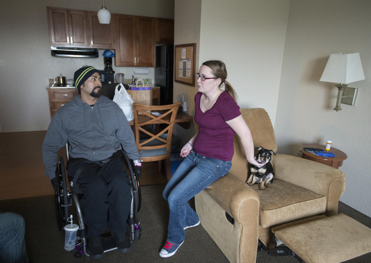 Juan Rubio, left, talks with his wife, Lindsey Rubio, while joined by their dog, Ruby, at Candlewood Suites near the Portland International Airport after getting out of the hospital on Dec. 13. He spent six weeks in the hospital after he was injured on the job at a Clark County dairy farm.