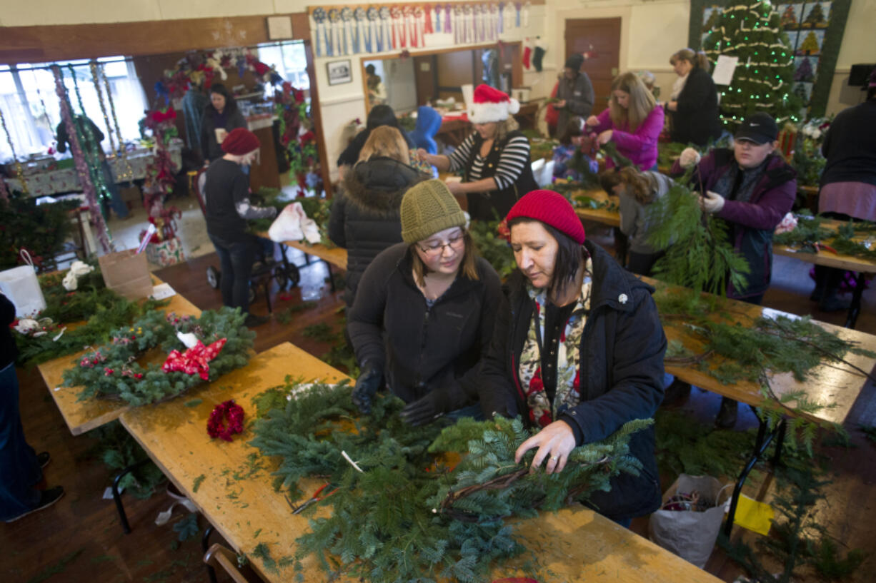 Camille Shelton gives her opinion to her mother, Angelene Shelton, as they assemble wreaths Sunday afternoon during a free wreath-making event at the Venersborg community center in the Battle Ground area. The Ridgefield women say the event is a family tradition.