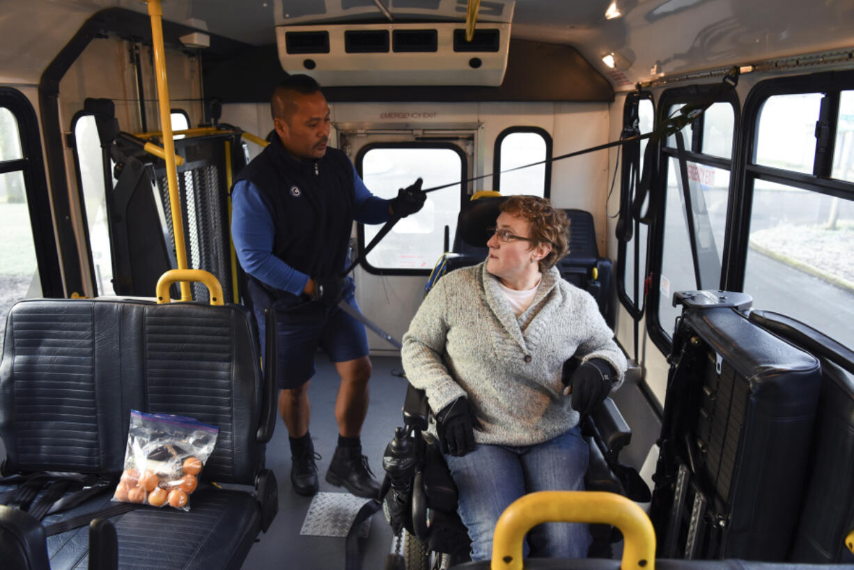 C-Van driver Jaime Somosot, left, readies a restraint for passenger Kristine Graham before driving her to Clark College.