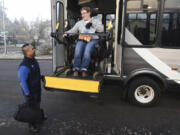 C-Van driver Jaime Somosot, left, helps Kristine Graham into the C-Van bus. C-Van is a costly but increasingly popular service the transit agency offers to people with mobility issues.