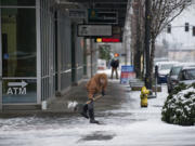 Jerrad Isch of Vancouver shovels ice and snow to clear a pathway to Umpqua Bank for customers in downtown Vancouver on Jan. 4. Local road crews are preparing to take to the streets Monday morning should the threat of snow hold true.