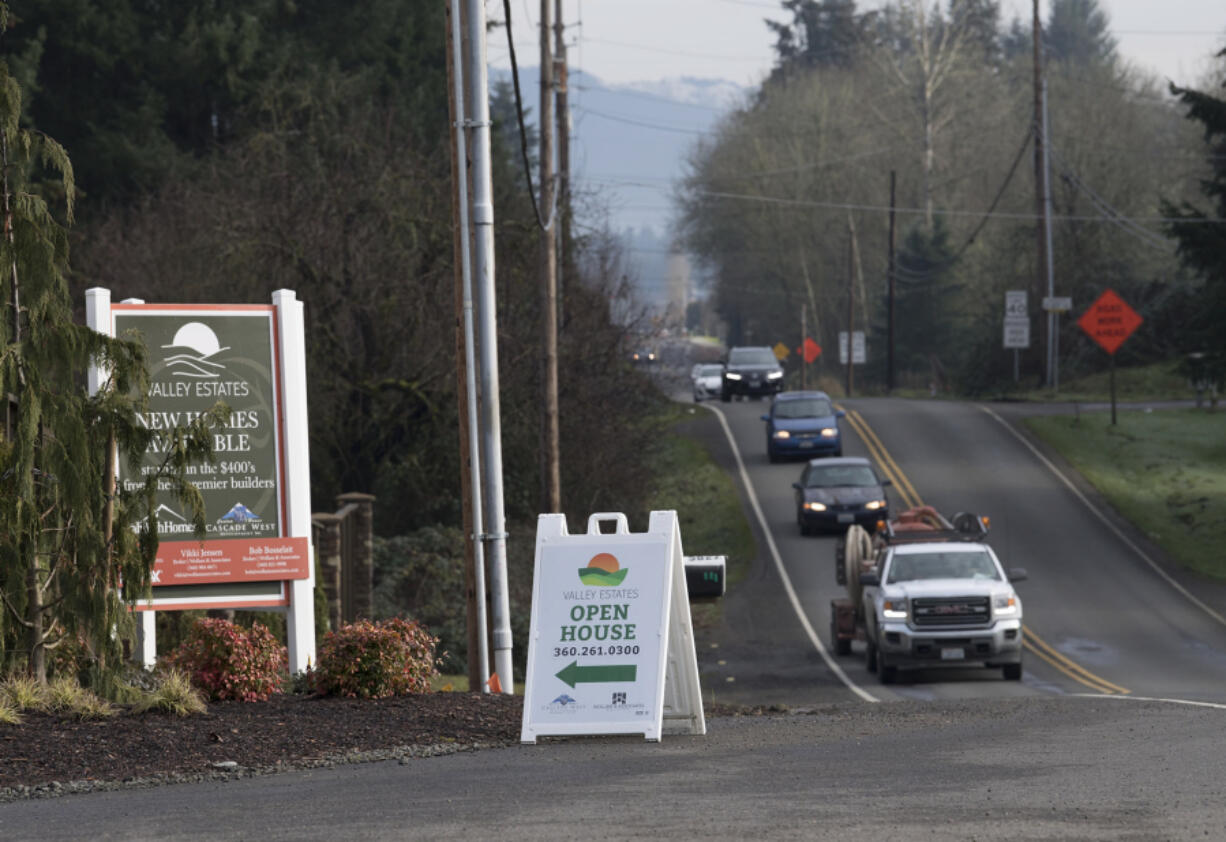 Traffic traveling on Northeast 119th Street passes signs advertising homes for sale. The area around the street has been growing, and the roadway is now being improved to keep up.