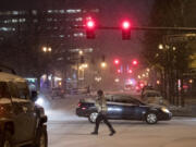 Pedestrians and motorists navigate through downtown Vancouver in the snow Wednesday evening.