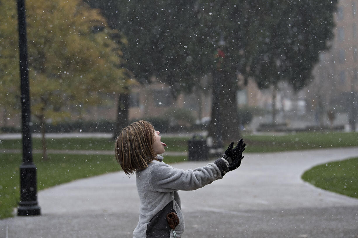 Delainey Poe, 7, of Vancouver catches snowflakes on her tongue while welcoming the snowfall at Esther Short Park on Thursday afternoon, Dec. 8, 2016.