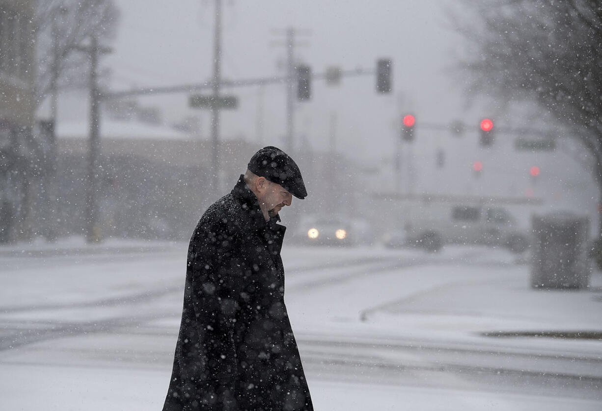 Kevin Weaver of Vancouver bundles up in a black coat and hat while trying to stay warm in the snow in downtown Vancouver on Thursday afternoon, Dec. 8, 2016.