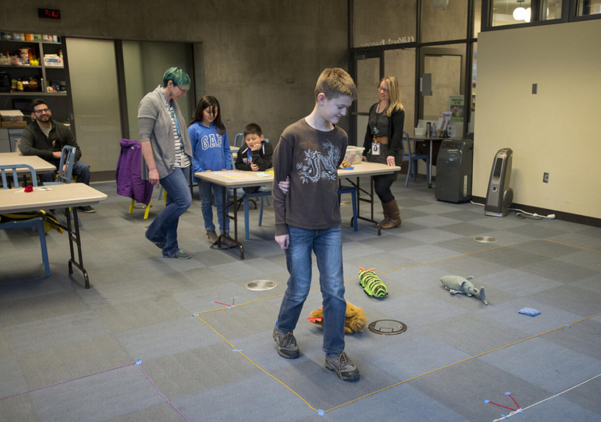 Javan Sheaves, 11, of Vancouver, center, pretends to be a robot while other students give him specific instructions during the Hour of Code event at Vancouver Community Library on Thursday afternoon. The internet was down at the library, meaning experiential learning librarian Jamie Bair created an activity to mimic basic programming.