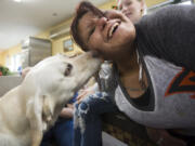 Enelida Acevedo gets a lick from Limon, a therapy dog at Share&#039;s family shelter in Hazel Dell on Saturday. DoveLewis&#039; therapy dogs are visiting the shelter to provide emotional support and comfort during the holidays, which are especially hard on homeless families.