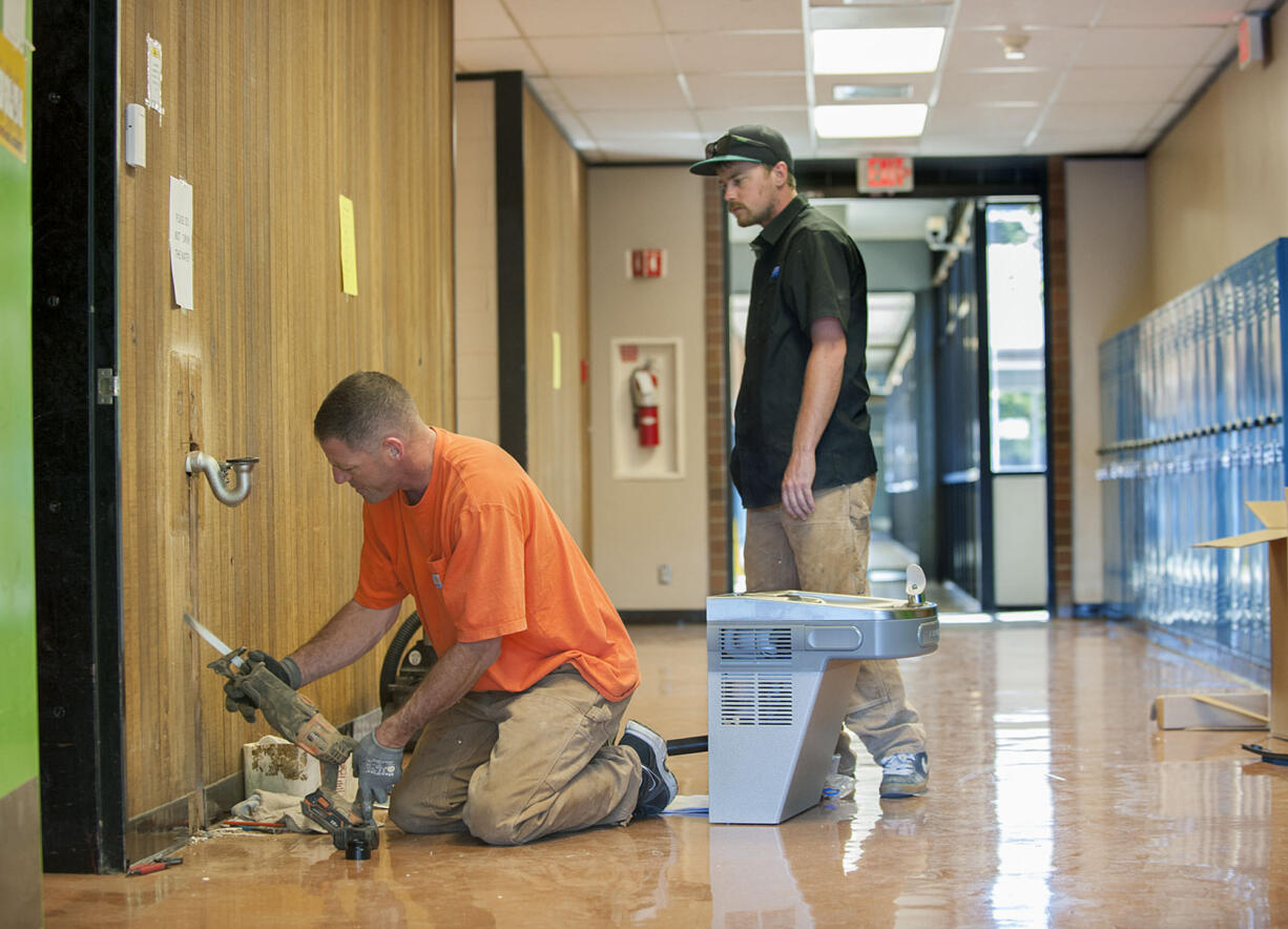 Ryan Romilly, left, and Jamie Wisenbaugh of Sarkinen Plumbing install a new water fountain in August that provides filtered water for students at View Ridge Middle School in Ridgefield.