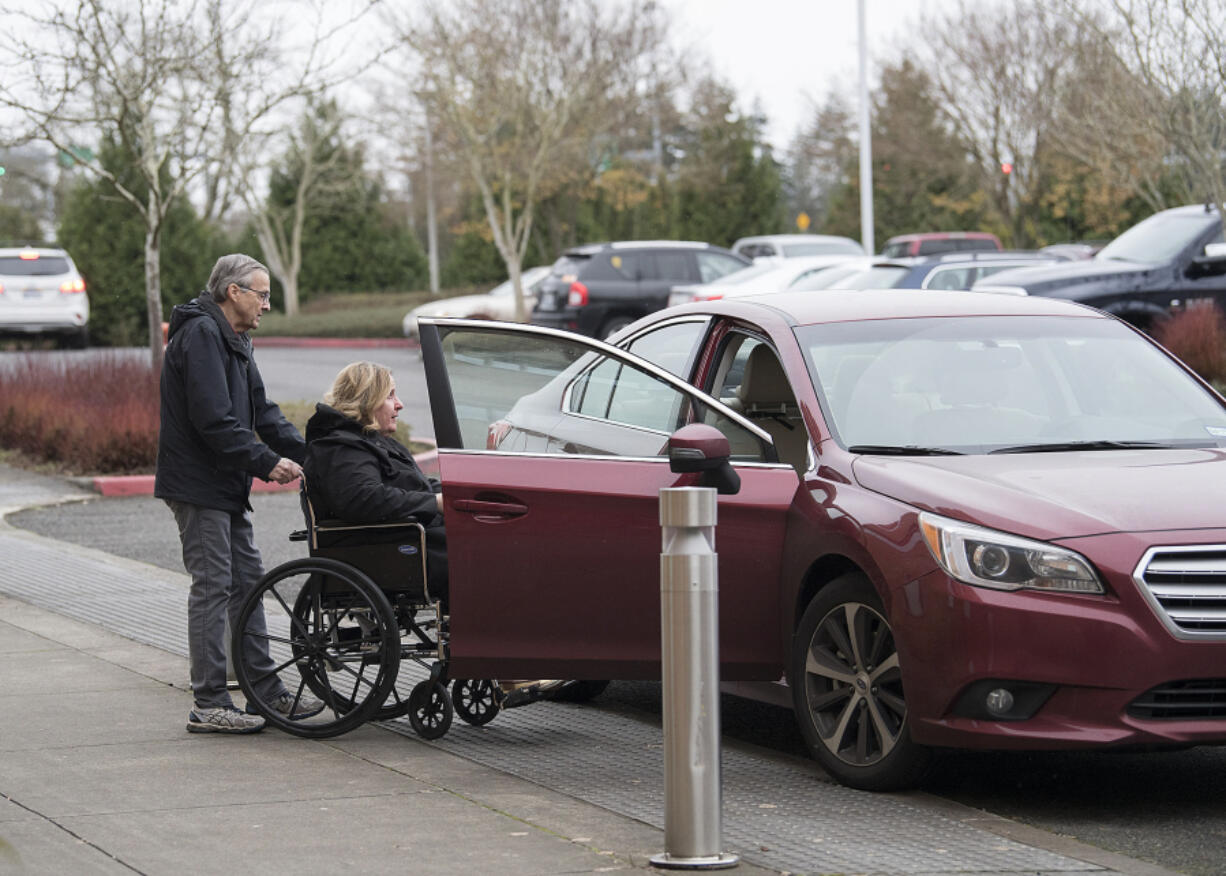 John Cummings of Vancouver pushes Linda Stithem in a wheelchair from her radiation appointment Dec. 14 at Legacy Salmon Creek Medical Center to his awaiting car. Cummings provides Stithem with rides to and from her daily appointments through the American Cancer Society&#039;s Road to Recovery program.