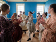 Volunteers in 1840s costume perform a line dance at Christmas at Fort Vancouver on Saturday.