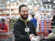 Costco employee Mathew Rios hands a receipt to a customer at checkout Tuesday in Vancouver. Rios, who has been a Costco employee for 22 years, helped save the life of an elderly woman Friday, after she collapsed in the checkout line at the store. He administered CPR for more than five minutes.