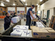 Camas-Washougal firefighter Jeff Martizia, center, loads packages of toys and food Wednesday at Station 42. They will be distributed to families in need around Camas and Washougal.