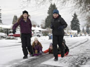 Grace Hopkins, 13, left, enjoys the winter weather Thursday afternoon with Maggie Hopkins, 7, Julia Blevins, 13, Tate Hopkins, 12, and Finley Reudink, 5, on the sled to the right, while they make their way along a slick Northwest Daniels Street.