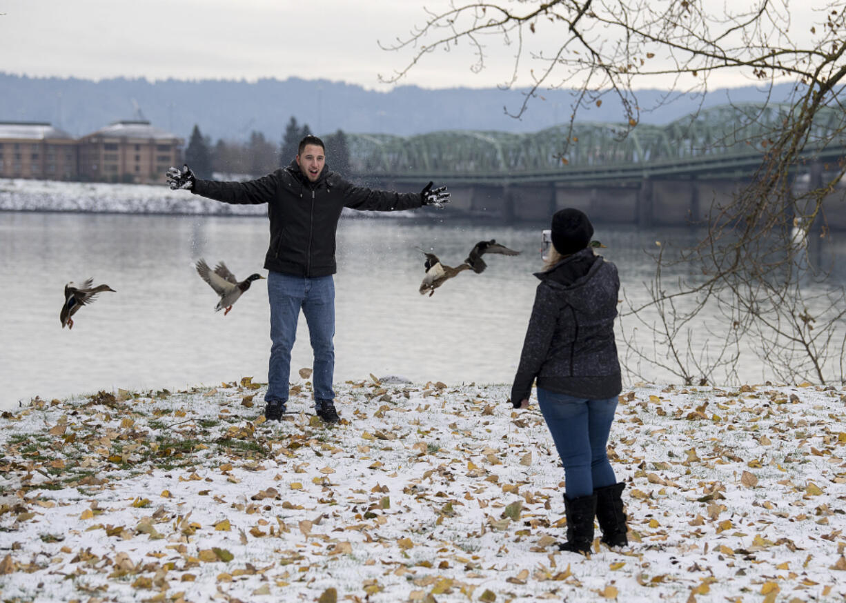 Zach Perez of Arizona, left, enjoys the winter weather as his girlfriend, Makayla Rehanek, snaps his photo Thursday afternoon at the  Vancouver Waterfront. The couple was in the Northwest house-sitting and visiting family for the holidays.