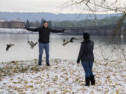 Zach Perez of Arizona, left, enjoys the winter weather as his girlfriend, Makayla Rehanek, snaps his photo Thursday afternoon at the  Vancouver Waterfront. The couple was in the Northwest house-sitting and visiting family for the holidays.