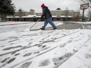 Lincoln Elementary School building operator Gene Boyer clears the sidewalk outside the school on Dec. 15, one of four snow days already this school year.