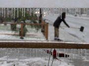 Icicles hang from a yard sign as Gloria Winner, 13, shovels ice from the sidewalk outside her Vancouver home to make the area safer for pedestrians Friday afternoon.