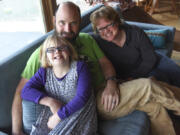 Adara Morgan, 10, who has Down syndrome, left, snuggles on the couch with her parents, David Morgan, center, and Abby Braithwaite, at their home in Ridgefield on Friday.