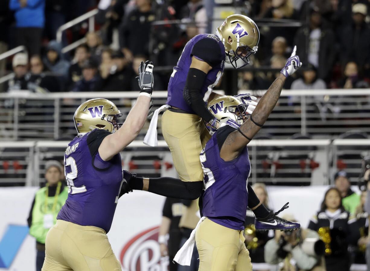 Washington tight end Darrell Daniels, right, celebrates his touchdown catch with teammates Aaron Fuller, center, and Jake Eldrenkamp during the first half of the Pac-12 Conference championship game against Colorado in Santa Clara, Calif. Alabama will play Washington and Ohio State is set to face Clemson in the College Football Playoff semifinals, announced Sunday, Dec. 4, 2016.