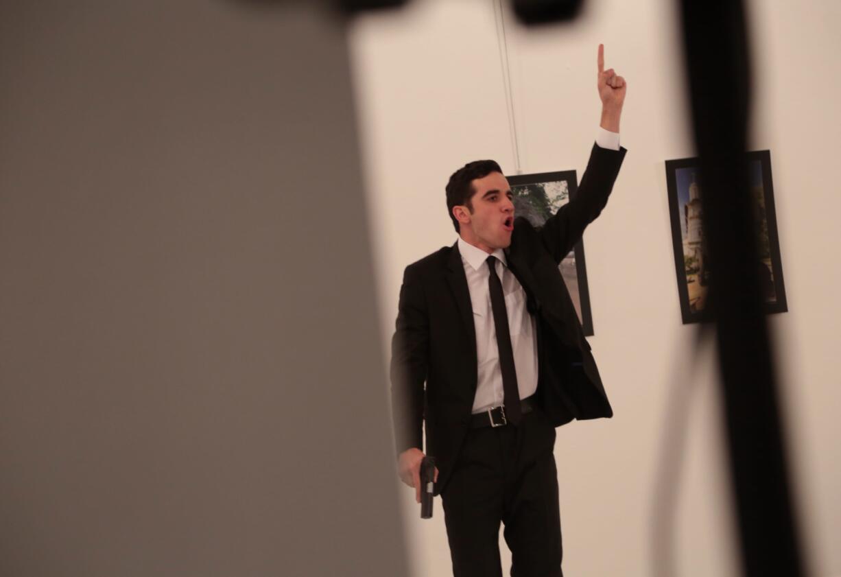 An unnamed gunman gestures after shooting the Russian Ambassador to Turkey, Andrei Karlov, at a photo gallery in Ankara, Turkey, Monday, Dec. 19, 2016. A gunman opened fire on Russia's ambassador to Turkey at a photo exhibition on Monday. The Russian foreign ministry spokeswoman said he was hospitalized with a gunshot wound.