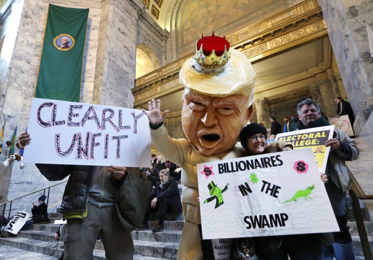 Jo Walter, of Bremerton, Wash., wears a large Donald Trump head mock-up as she protests Electoral College voting Monday, Dec. 19, 2016, in Olympia, Wash. Members of Washington state's Electoral College met at noon Monday in the Capitol to complete the constitutional formality.