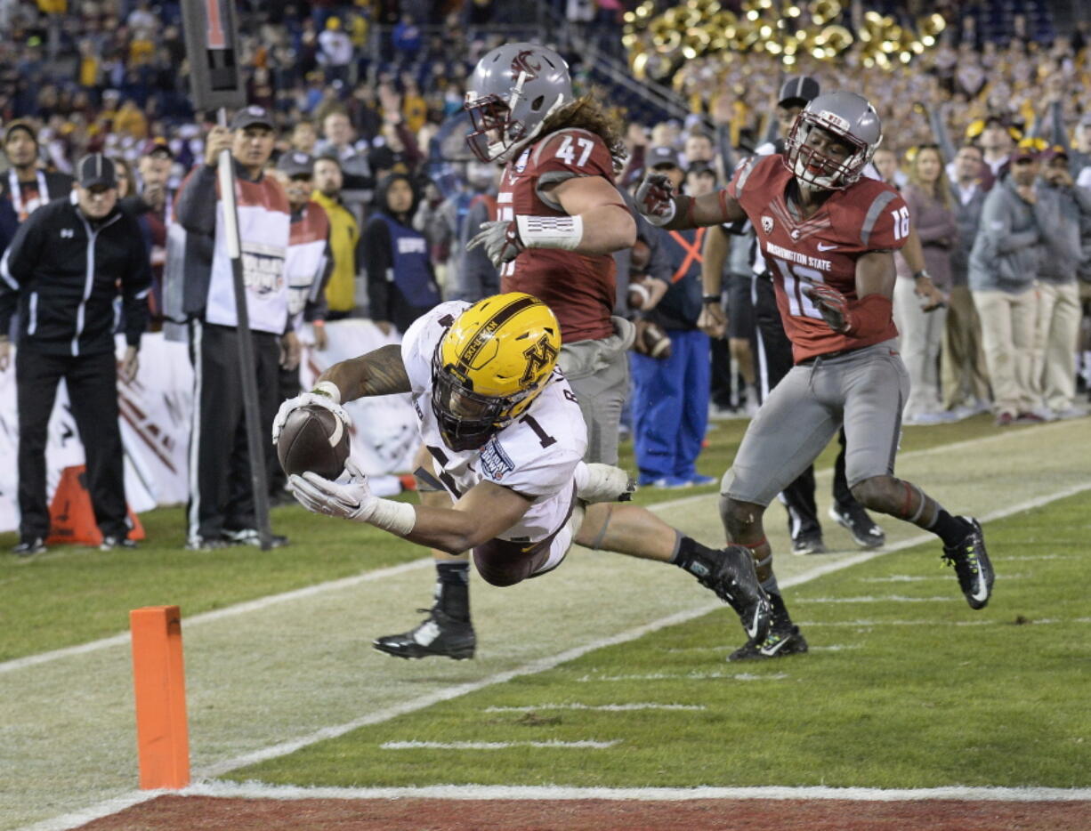 Minnesota running back Rodney Smith (1) dives into the end zone for a touchdown past the defense of Washington State linebacker Peyton Pelluer (47) and cornerback Treshon Broughton (16) during the second half of the Holiday Bowl NCAA college football game, Tuesday, Dec. 27, 2016, in San Diego.