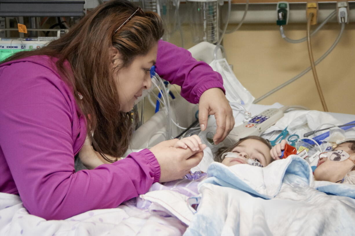 Aida Sandoval and her daughters, Eva, left, and Erika, right, in Palo Alto, Calif. The conjoined California twins that were separated Dec. 6 following a 17-hour marathon surgery have been reunited for the first time since the operation. The 2-year-old Sacramento area girls were born conjoined from the chest down and shared a bladder, liver, parts of their digestive system and a third leg.