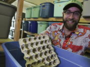 Austin Miller poses Dec. 1 with some of the crickets he raises in bins inside a warehouse in Eugene, Ore. It takes six to eight weeks for the crickets to grow into adult bugs. Miller breeds, raises, freezes, boils, bakes and packages the small insects for humans to buy -- and eat.