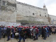 Christian pilgrims wearing red Santa hats wait in line to enter the Church of the Nativity, built atop the site where Christians believe Jesus Christ was born, on Christmas Eve, Dec. 24, in the West Bank City of Bethlehem.