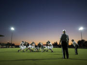 Members of the Battle Ground varsity team face off during a scrimmage as stadium lights illuminate the field Thursday evening, Aug. 25, 2016 at Battle Ground High School.