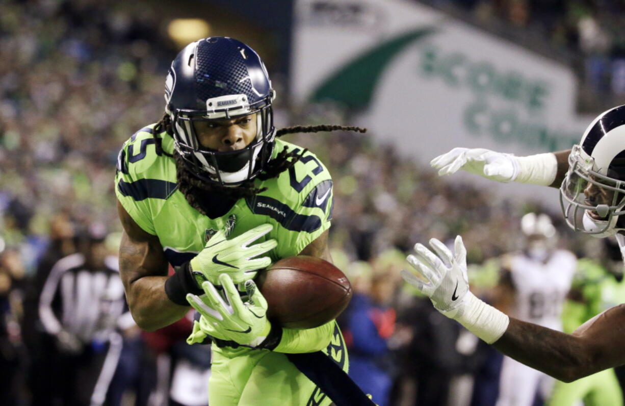 Seattle Seahawks cornerback Richard Sherman, left, bobbles a pass intended for Los Angeles Rams wide receiver Kenny Britt, right, in the first half of an NFL football game, Thursday, Dec. 15, 2016, in Seattle.