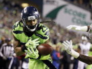 Seattle Seahawks cornerback Richard Sherman, left, bobbles a pass intended for Los Angeles Rams wide receiver Kenny Britt, right, in the first half of an NFL football game, Thursday, Dec. 15, 2016, in Seattle.