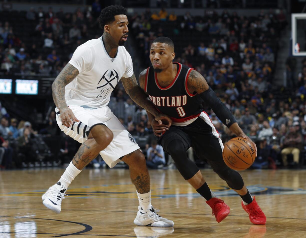 Portland Trail Blazers guard Damian Lillard , right, drives to the basket as Denver Nuggets forward Wilson Chandler (21) defends in the first half of an NBA basketball game Thursday, Dec. 15, 2016, in Denver.