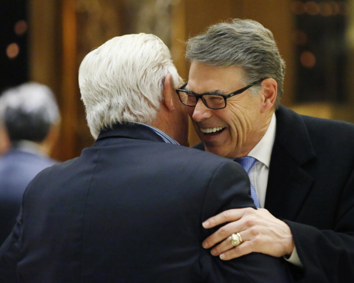 Former Texas Gov. Rick Perry, right, laughs as he hugs an unidentified man in the lobby at Trump Tower on Monday in New York.