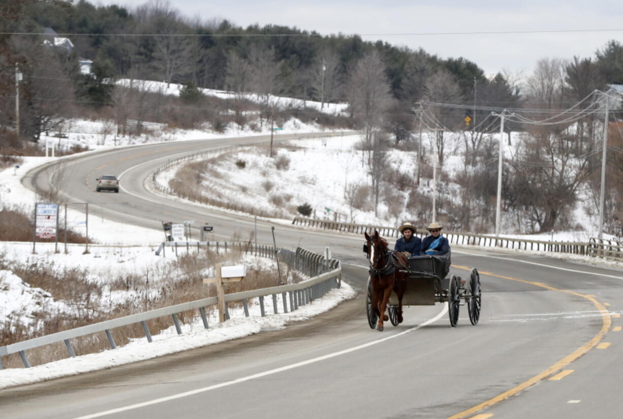 People ride on a buggy Monday on Route 417 in Woodhull, N.Y.