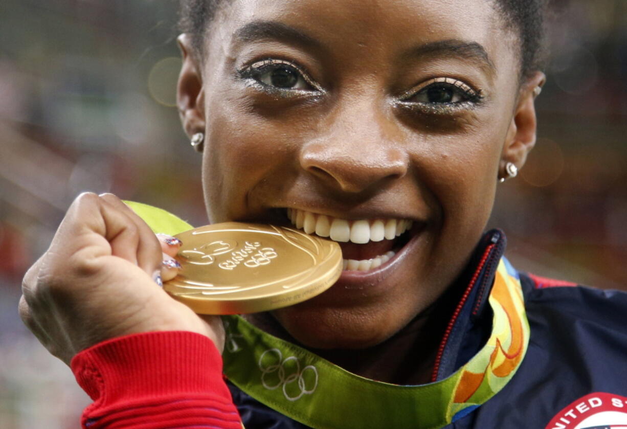 United States' Simone Biles bites her gold medal for the artistic gymnastics women' individual all-around final at the 2016 Summer Olympics in Rio de Janeiro, Brazil. Briles was selected as the AP Female Athlete of the Year, on Monday, Dec. 26, 2016.