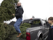 Gregg Marshall, left, unloads a tree at McFarlane&#039;s Bark in the Orchards area while Eric Knotts watches on the Boy Scouts&#039; Christmas tree recycling day in 2014.